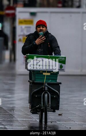 London, Großbritannien. Januar 2021. A, Schlüsselarbeiter, Fahrrad Kurier liefert Plastikhandschuhe. Leicester Square ist ruhig, aber nicht leer - der erste Tag der nationalen Lockdown 3. Dies ersetzt Tier-4-Beschränkungen und die Regierung Anweisung ist für alle zu Hause zu bleiben, um den Druck auf die NHS zu sparen. Kredit: Guy Bell/Alamy Live Nachrichten Stockfoto