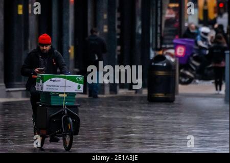 London, Großbritannien. Januar 2021. A, Schlüsselarbeiter, Fahrrad Kurier liefert Plastikhandschuhe. Leicester Square ist ruhig, aber nicht leer - der erste Tag der nationalen Lockdown 3. Dies ersetzt Tier-4-Beschränkungen und die Regierung Anweisung ist für alle zu Hause zu bleiben, um den Druck auf die NHS zu sparen. Kredit: Guy Bell/Alamy Live Nachrichten Stockfoto