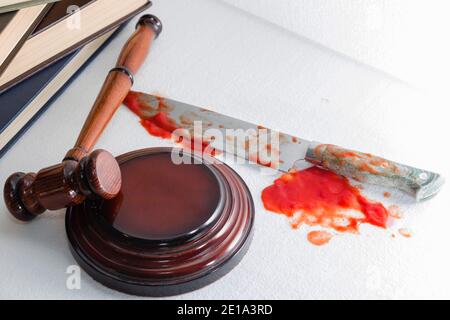 Konzeptuelles Bild eines scharfen Messers mit Blut auf dem Hintergrund des Richterhammers. Gerechtigkeit. Stockfoto