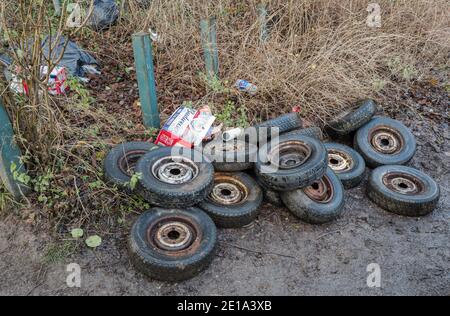 Stapel von gebrauchten Autoreifen auf einer Landstraße gedumpt. Stockfoto