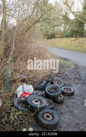 Stapel von gebrauchten Autoreifen auf einer Landstraße gedumpt. Stockfoto