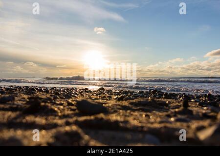 Toller Sonnenuntergang am Strand mit endlosem Horizont und Steinen im Vordergrund Stockfoto