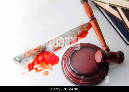 Konzeptuelles Bild eines scharfen Messers mit Blut auf dem Hintergrund des Richterhammers. Gerechtigkeit. Stockfoto