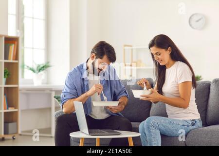 Mann und Frau untersuchen das Essen in ihren Händen, das sie vom Lieferservice bestellt haben. Stockfoto