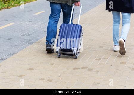 Ein Mann und eine Frau mit einem Koffer sind auf dem Bürgersteig. Tourismus und Reisen Stockfoto