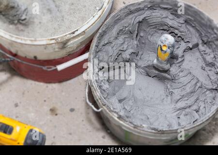 Dekorativer Zementputz und eine Kelle in einem Baueimer bereit zum Verputzen. Stockfoto