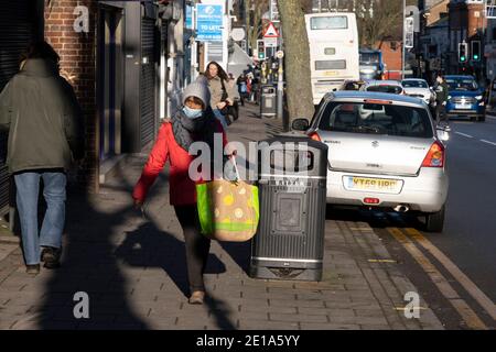 Am letzten Tag des Jahres gehen maskierte Menschen auf der Kings Heath High Street einkaufen, da viele Geschäfte am 31. Dezember 2020 in Birmingham, Großbritannien, geschlossen bleiben und die Fensterläden aufgrund der Beschränkungen des Tier-4-Coronavirus heruntergefahren sind. Kleine Unternehmen haben sich mit der Covid-19-Pandemie zu kämpfen und viele haben ihre Geschäfte geschlossen, da sich die Rezession in der Wirtschaft mit der andauern Krise verschärft. Stockfoto