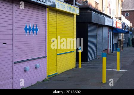 Am letzten Tag des Jahres bleiben unabhängige Geschäfte an der York Road in Kings Heath geschlossen, mit Rollläden wegen Tier-Four-Coronavirus-Beschränkungen am 31. Dezember 2020 in Birmingham, Großbritannien. Kleine Unternehmen haben sich mit der Covid-19-Pandemie zu kämpfen und viele haben ihre Geschäfte geschlossen, da sich die Rezession in der Wirtschaft mit der andauern Krise verschärft. Stockfoto