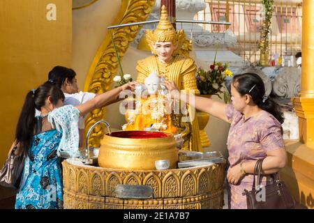 Frauen verehren sich in der Shwedagon Pagode und gießen Wasser auf das Buddha-Gleichnis. Stockfoto