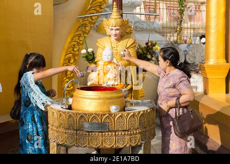 Frauen verehren sich in der Shwedagon Pagode und gießen Wasser auf das Buddha-Gleichnis. Stockfoto