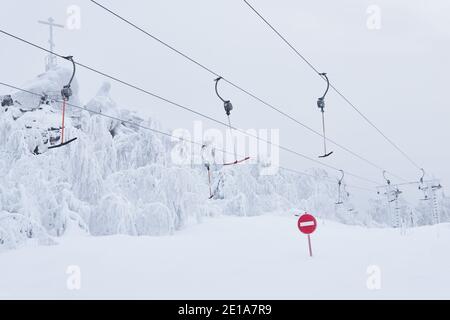 Verbotsschild Keine Einfahrt vor dem Hintergrund eines Leere Ski T-Bar Oberfläche Lifte auf einer verschneiten Skipiste Stockfoto