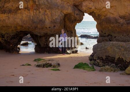 Praia da Rocha, Algarve, Portugal - Februar 2019: Blick auf die Tunnel, die sich in den großen Felsen des Strandes bilden, wo ein Tourist ein Foto macht Stockfoto