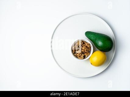 Reife Avocado und Zitrone und Walnüsse auf weißem Hintergrund. Draufsicht mit Platz zum Kopieren. Stockfoto