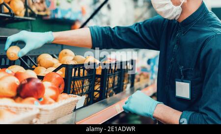 verkäufer in einer Schutzmaske vor der Theke mit Obst stehen. Stockfoto