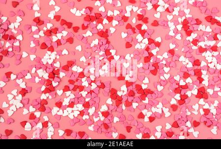 Romantischer Hintergrund mit kleinen Herzen auf rosa Hintergrund. Der Blick von oben. Stockfoto