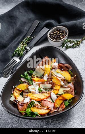 Salat mit Prosciutto, Pfirsich und Rucola. Kalte Snacks. Grauer Hintergrund. Draufsicht Stockfoto