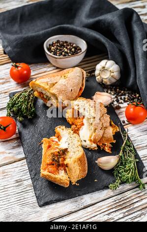 Baguette gefüllt mit Auberginen, Tomaten und Käse. Ein köstliches vegetarisches Mittagessen, leckere Snacks, hausgemachtes Sandwich. Grauer Hintergrund. Draufsicht Stockfoto