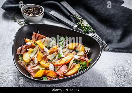 Salat mit Prosciutto, Pfirsich und Rucola. Kalte Snacks. Grauer Hintergrund. Draufsicht Stockfoto