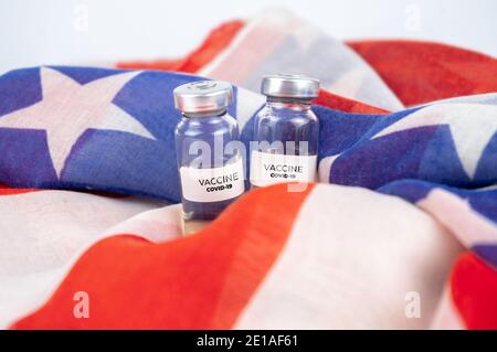 Zwei Flaschen mit Covid-19-Impfstoff. US-Flagge im Hintergrund Stockfoto