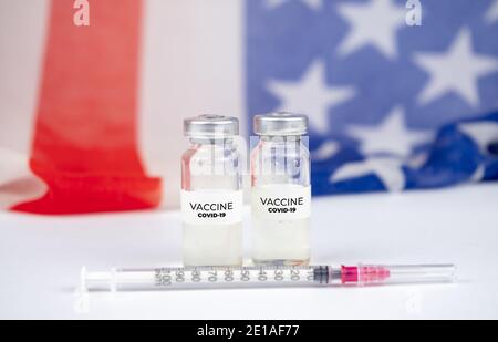 Zwei Flaschen mit Covid-19-Impfstoff. US-Flagge im Hintergrund Stockfoto
