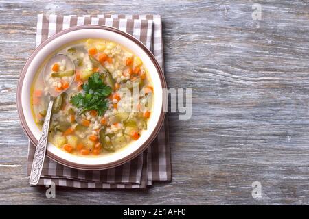 Vegane Suppe mit eingelegten Gurken und Perlgerste, rassolnik. Traditionelle hausgemachte russische Küche. Auf einem Holztisch Stockfoto