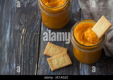 Gesunde rohe Orangenmarmelade mit getrockneten Aprikosen in einem Glas mit Cookies auf einem Holztisch. Diät-Essen. Selektiver Fokus, Freiraum. Rustikaler Stil Stockfoto
