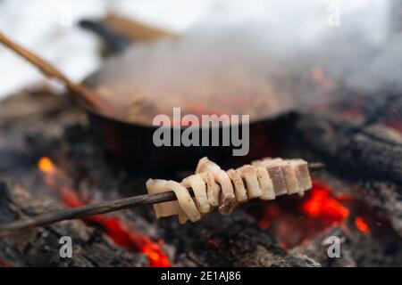 Schmalz Kochen auf Stock über dem Feuer im Winterwald Lager Stockfoto