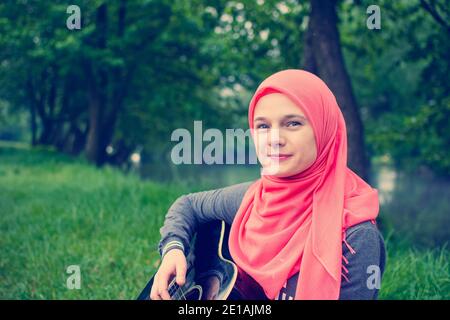 Muslim Mädchen mit blauen Augen spielen akustische Gitarre Stockfoto