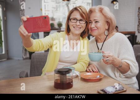 Glückliche reife Frau nimmt Selfies mit ihrer älteren Mutter an Das Café Stockfoto