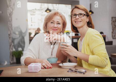 Glückliche ältere Mutter und ihre Erwachsene Tochter beim Kaffee zusammen im Café. Ältere Frau trifft ältere Mutter zum Frühstück Stockfoto