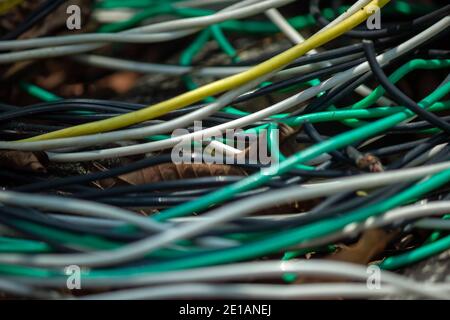 Nahaufnahme mehrerer elektrischer Drähte, die gebogene Linien bilden, mit einem Viel Chaos, als wären sie verlassen Stockfoto