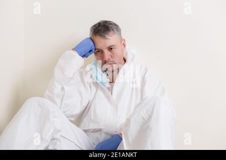 Ein trauriger Arzt sitzt auf dem Boden im Flur des Krankenhauses. Gesundheitspersonal während der Covid19-Coronavirus-Pandemie Stockfoto