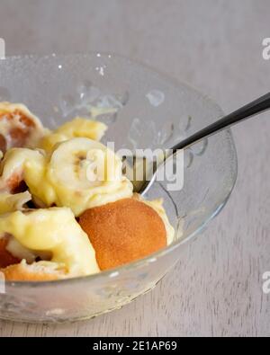 Nahaufnahme einer Portion Bananenpudding mit Pudding, Vanilleplätzchen und in Scheiben geschnittenen Bananen in einer Schüssel mit Löffel serviert. USA. Stockfoto