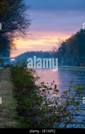 Flusskanal Biegen mit Grasbänken und wilden Blumen und Bäumen in einer malerischen Landschaft an einem nebligen Herbstmorgen Sonnenaufgang Tag. Hochwertige Fotos Stockfoto