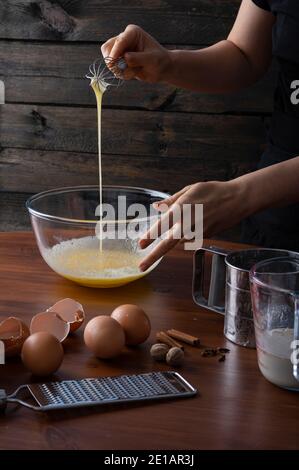 Eine Frau, die Eier und Gewürze in einer Schüssel zuquirlt Eine Hüttenküche Stockfoto