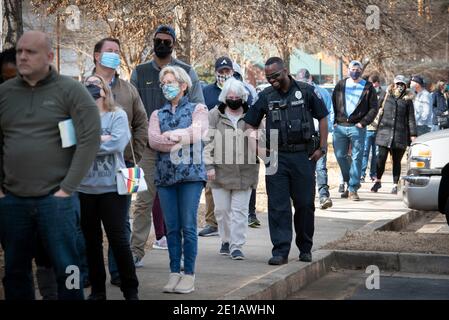 Woodstock, USA. Januar 2021. Wahlkampflinien am Wahltag in Cherokee County, Georgia, einer stark republikanischen Region des Staates. Im Bild: Ein Polizeibeamter der Stadt Woodstock begleitet einen älteren und behinderten Wähler an die Spitze der Schlange. Quelle: Robin Rayne/ZUMA Wire/Alamy Live News Stockfoto