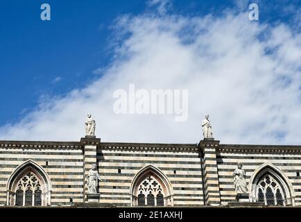 Oberer Teil der rechten Seite der Kathedrale von Siena (13. Jahrhundert) mit spitzen Fenstern und Statuen von Heiligen auf der Spitze gegen blauen Himmel, Toskana, Italien Stockfoto