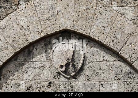 Nahaufnahme eines alten Steinreliefs mit einer Schere, Symbol der Barbiere, in der Altstadt von Siena, Toskana, Italien Stockfoto