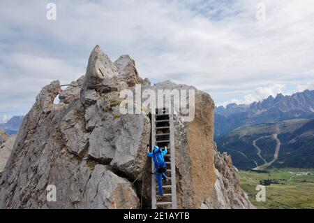 Klettererin in blauem Outfit, die Klettersteige in den Dolomiten aufsteigt Stockfoto