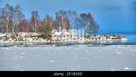 Eis und Schnee fangen an, das Land und den Lake Superior im Vordergrund zu überziehen, während das Wasser noch weiter draußen offen ist. Stockfoto