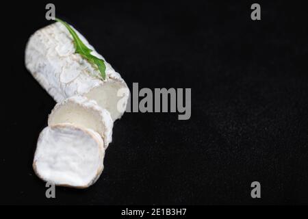 Weißer Ziegenkäse auf schwarzem Hintergrund. Frischer Ziegenkäse mit Kopierraum, in Stücke geschnitten Stockfoto