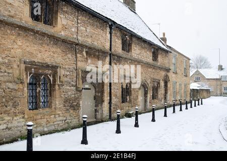 Die Großen Almshäuser entlang der Kirchenstraße im Dezember Schnee. Burford, Cotswolds, Oxfordshire, England Stockfoto