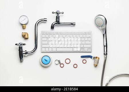 Komposition mit Klempnerartikeln und Computertastatur auf weißem Hintergrund Stockfoto