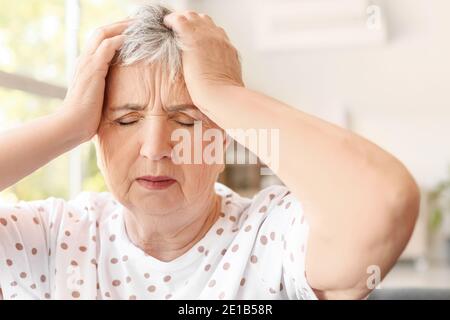 Gestresste ältere Frau, die an Kopfschmerzen leidet Stockfoto