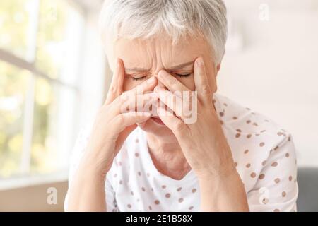 Gestresste ältere Frau, die an Kopfschmerzen leidet Stockfoto