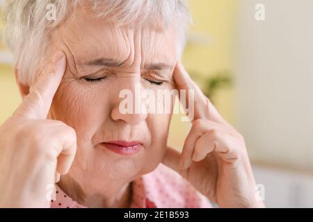 Gestresste ältere Frau, die an Kopfschmerzen leidet Stockfoto