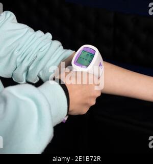 Messung der Körpertemperatur mit einem elektronischen Infrarot-Digitalthermometer für alle Büromitarbeiter. Coronavirus-Prävention Stockfoto