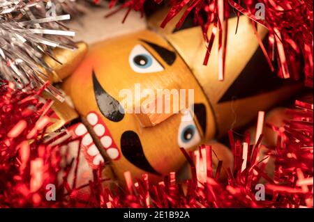 Holzfigur in Form eines Soldaten zum Hacken von Nüssen umgeben von farbigen Lametta und Haselnüssen in der Masse. Neujahr und Weihnachten. Nahaufnahme, Selecti Stockfoto