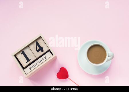 Eine Tasse Kaffee, Kalender Februar 14 und Spielzeug Herz auf rosa Hintergrund. Liebeskonzept, Valentinstag. Draufsicht, flach liegend, Kopierbereich. Stockfoto