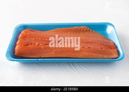 Frischer roher Lachs im Plastikbehälter Nahaufnahme auf Weiß Hintergrund Stockfoto
